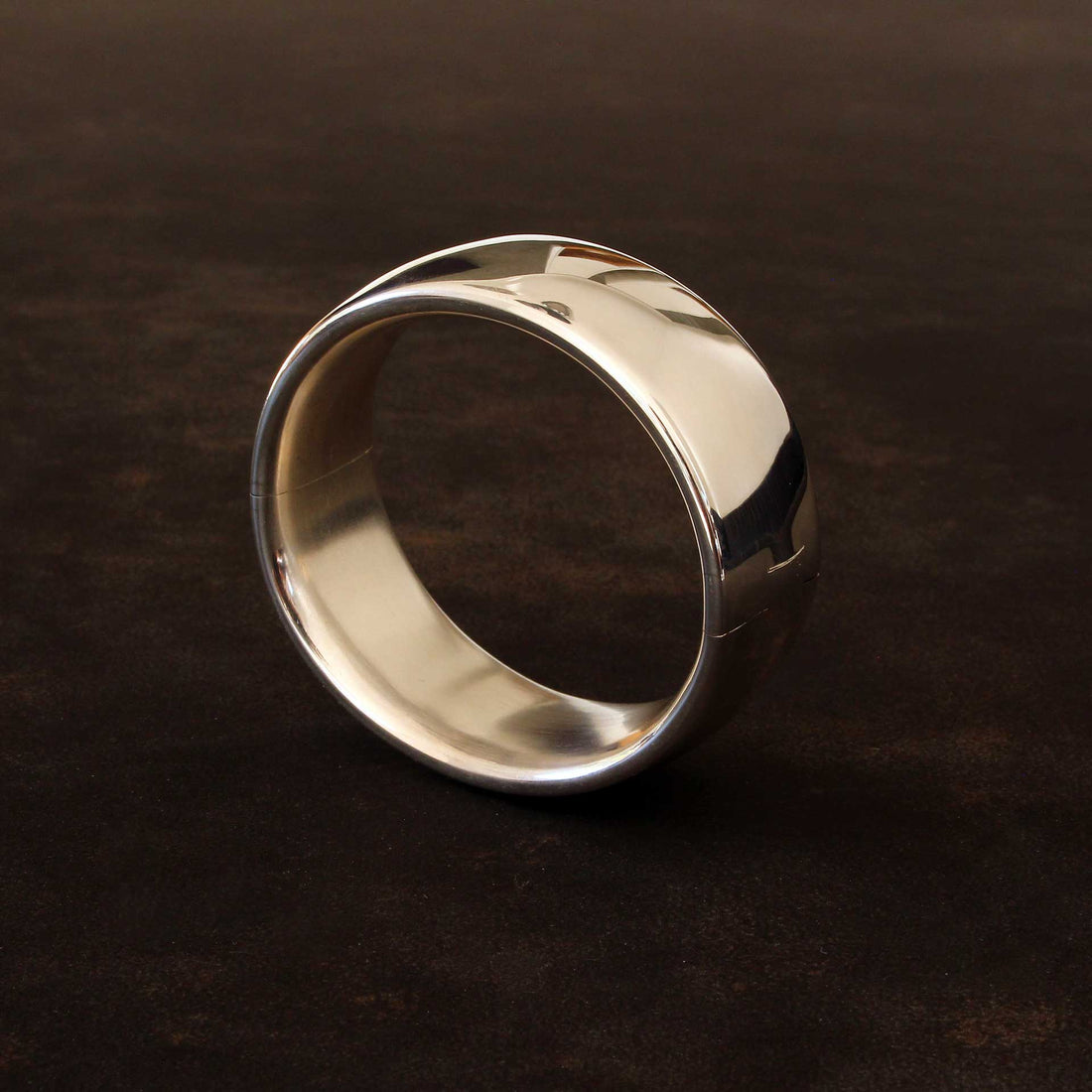 Massiver Unisex-Silberarmreif 25 mm breit aus 925 Sterlingsilber, hochglanzpoliert auf dunklem Stein präsentiert.