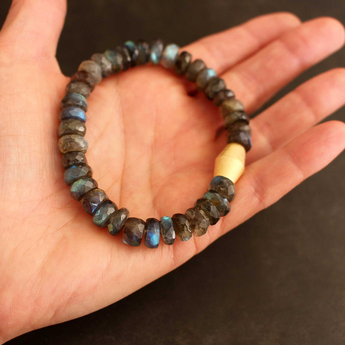 Nahaufnahme eines massiven Labradorit-Armbands, präsentiert auf einer geöffneten Handfläche, um die imposante Größe der 10-12mm facettierten Edelstein-Rondelle und die Wertigkeit der vergoldeten Silberschließe zu zeigen.