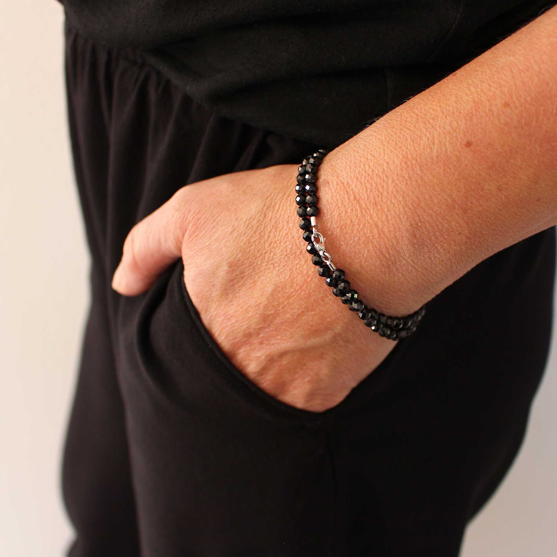 Das schwarze Spinell-Wickelarmband liegt doppelt gewickelt am Handgelenk an. Die facettierten Edelsteine und der Weißgold-Karabiner setzen elegante Akzente.