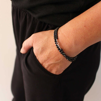 Das schwarze Spinell-Wickelarmband liegt doppelt gewickelt am Handgelenk an. Die facettierten Edelsteine und der Weißgold-Karabiner setzen elegante Akzente.